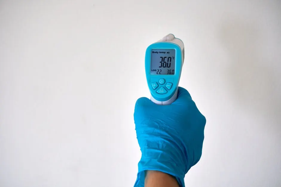 Healthcare worker checks temperature using an infrared thermometer. Ideal for health and medical contexts.